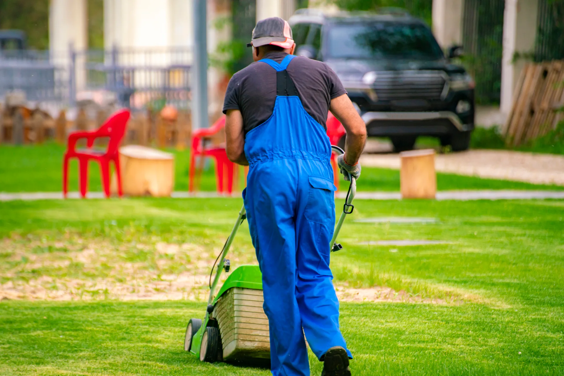 Field crew member mowing a suburban lawn with a push mower